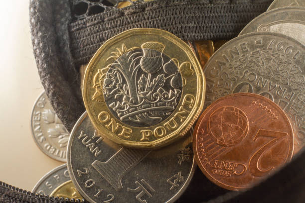 British one pound coin standing on its edge on top of a column of coins. No people.