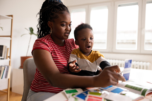 Young African American mother reading and playing preschool card games with her son