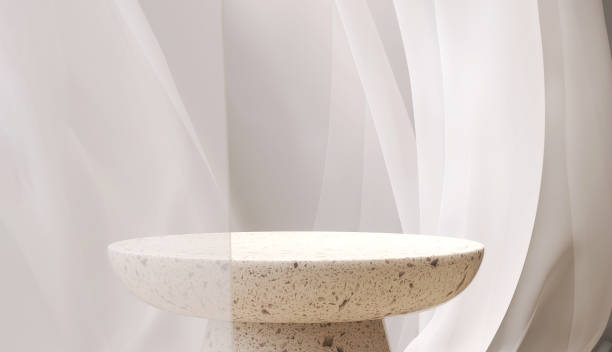 istock Empty modern round cream terrazzo podium side table in soft white blowing sheer cloth curtain drapery in sunlight 1490599562