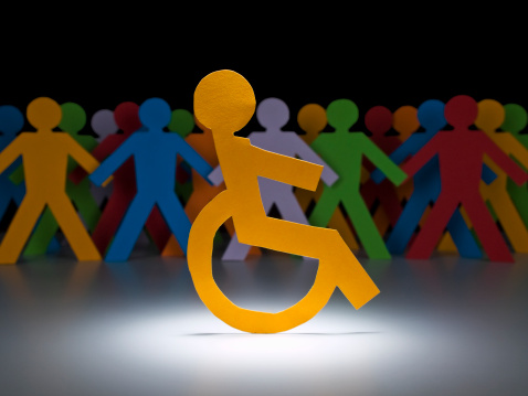 A disable paper figure stands under the spotlight on his wheelchair.
