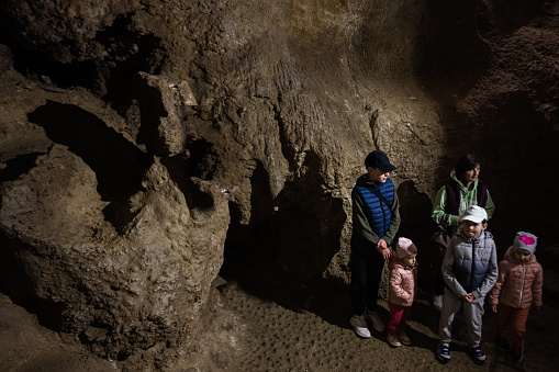 Family tourists walking in cave and explore it.