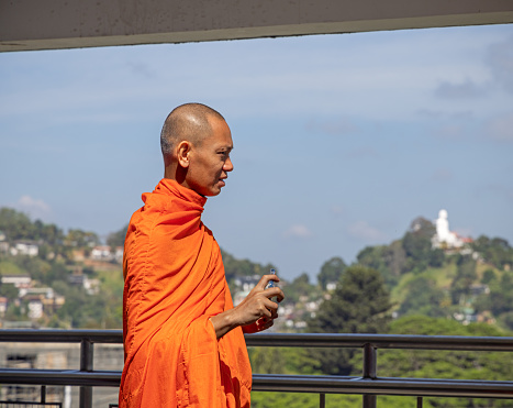 Kandy, Central Province, Province, Sri Lanka - February 25th 2023: Walking male buddhist monk in orange clothes in the holy city