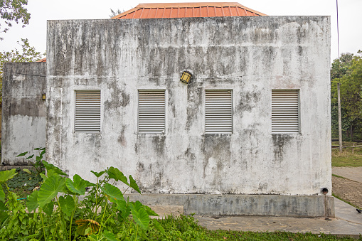 Tricomalee, Eastern Province, Province, Sri Lanka - March 4th 2023:  Building with a dirty white wall with four blinded windows