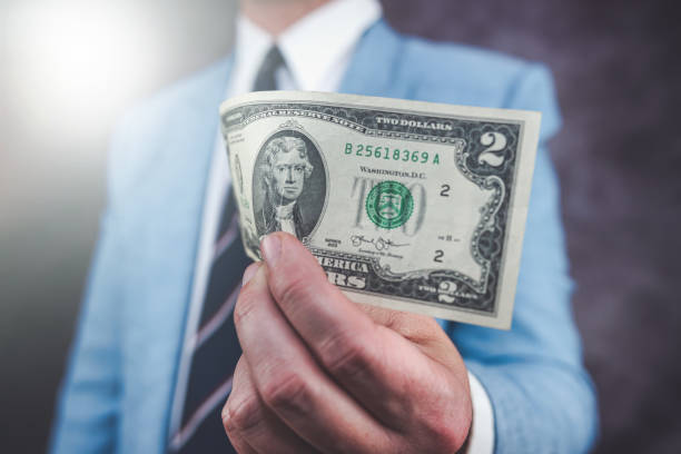 istock Closeup male hand holding 2 US dollar bills 1490601581