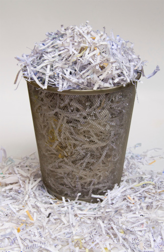 A waste basket overflowing with shredded paper.