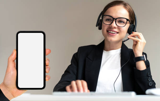 istock Online support and professional consultation concept, phone with blank screen in hand close-up, call centre representative in headset. 1490603997