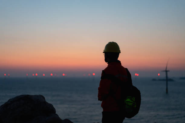Romantic sky at an offshore wind farm at dawn Engineer enjoys the beautiful scenery of wind farm by the sea offshore wind farm stock pictures, royalty-free photos & images