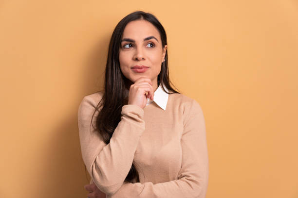 istock woman thinking and looking to the side in beige background. 1490612227