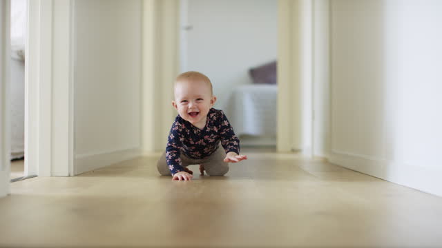 Happy baby girl sitting on flooring in corridor