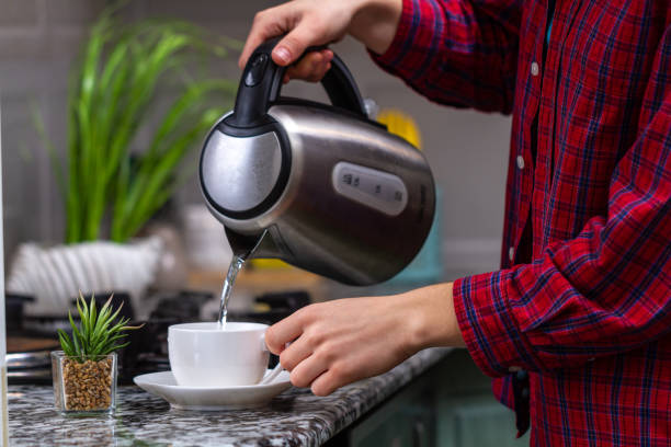 istock Person makes tea using boiling water from an electric kettle in kitchen at home. Time for breakfast 1490614743