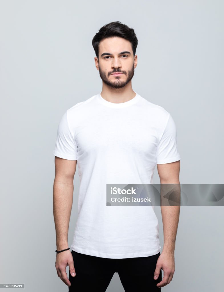 Portrait of handsome young man Handsome man wearing white t-shirt looking at camera. Studio shot, grey background. Men Stock Photo