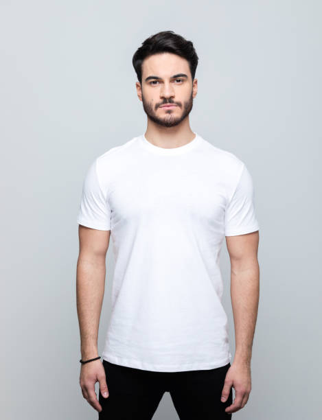 Portrait of handsome young man Handsome man wearing white t-shirt looking at camera. Studio shot, grey background. t shirt caucasian photography color image stock pictures, royalty-free photos & images