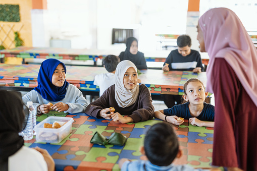 Group of school children eating snack in school canteen