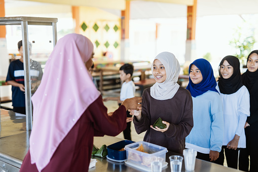 Group of school children eating snack in school canteen