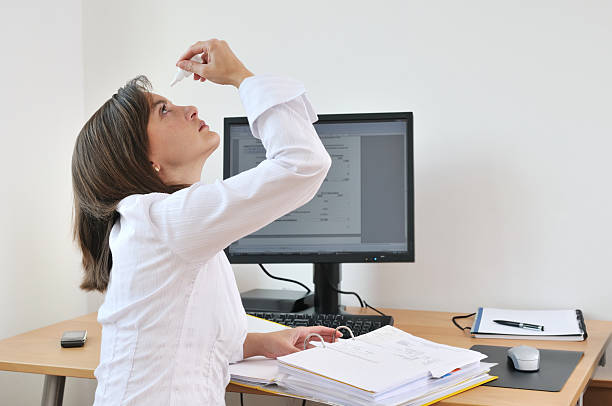 Young business person applying eyes drops