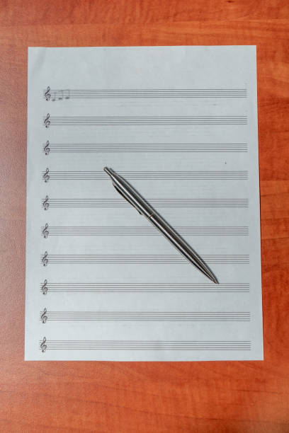 writing musical notes on sheet with quill pen and ink. music education. closeup