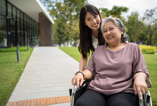 Asian careful caregiver or nurse taking care of the patient in a wheelchair. Concept of happy retirement with care from a caregiver and Savings and senior health insurance, a Happy family