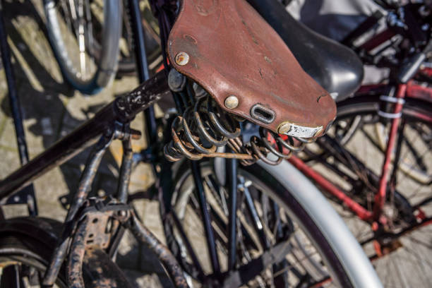 This captivating photo highlights a detailed view of an old leather bicycle saddle, marked by time and past adventures. The large springs supporting the saddle add a retro and robust aesthetic. Every crease and wear tells a story, bearing witness to the miles traveled and memories engraved in the leather. This saddle evokes an era when cycling was synonymous with elegance and exploration, reminiscent of the timeless charm of classic two-wheelers.