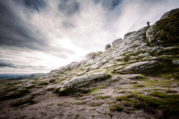 Man Stood Atop Of A Sloping Side Of Haytor Tor, Dartmoor A man stood on top of the rocky sloping side of Haytor Tor in Dartmoor. outcrop stock pictures, royalty-free photos & images