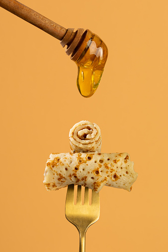 Two twisted pieces of crepe on dolden fork and pouring honey