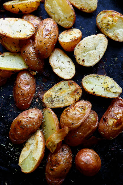 roasted potatoes wedges with herbs roasted potatoes wedges with herbs, food closeup gold potato stock pictures, royalty-free photos & images