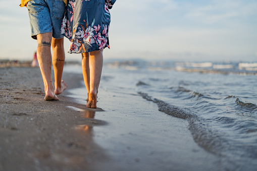Low section of a couple walking on the beach
