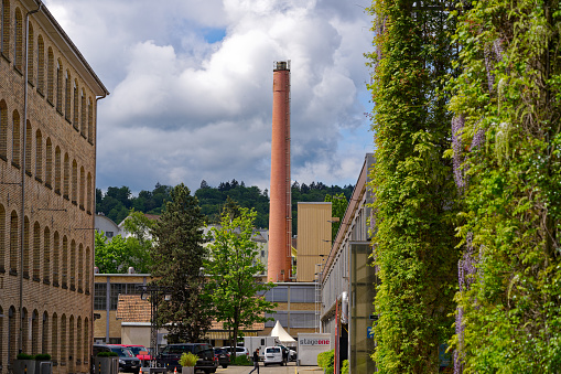 Former industrial buildings with brick wall chimney at City of Zürich district Oerlikon on a blue cloudy spring day. Photo taken May 12th, 2023, Zurich, Switzerland.
