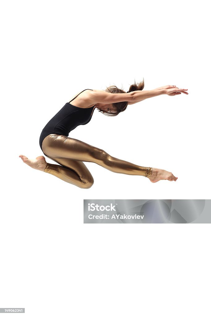 Woman dancer with black top and gold pants jumping modern style dancer posing on studio background  Dancing Stock Photo
