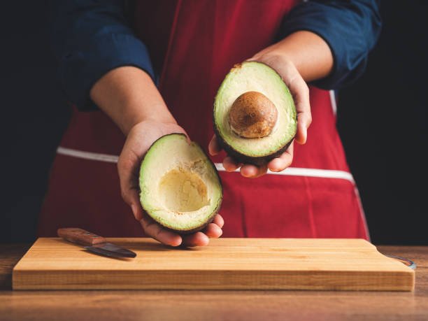 istock Close-up of hands holding a fresh avocado while standing in the kitchen. 1490623567