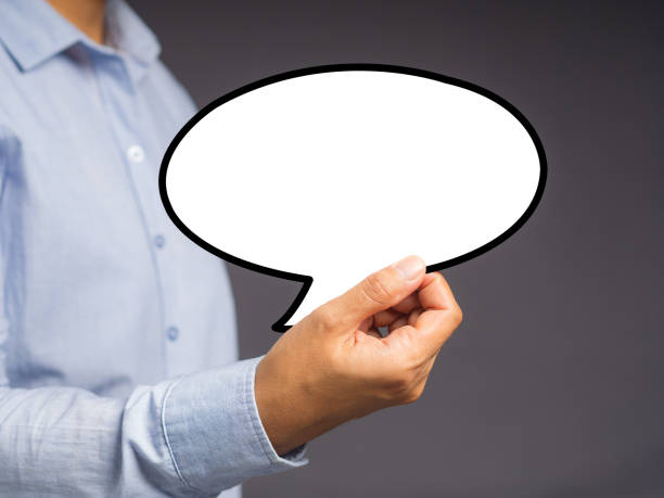 istock Hand holding of an empty white speech bubble against a gray background. 1490624249