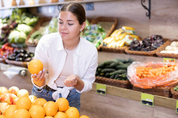 istock Delighted young woman purchaser choosing oranges in grocery store 1490626468