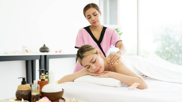 istock Relaxing young Asian woman lying down and closing her eyes on massage beds while receiving a massage from a therapist at an Asian luxury spa salon and a wellness center, waiting for Spa salon concept 1490627082