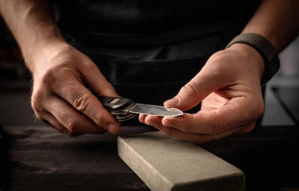 Man's hands with folding knife and sharpen stone tool Man's hands with folding knife and sharpen stone tool. master sharpening penknife on a grindstone penknife stock pictures, royalty-free photos & images