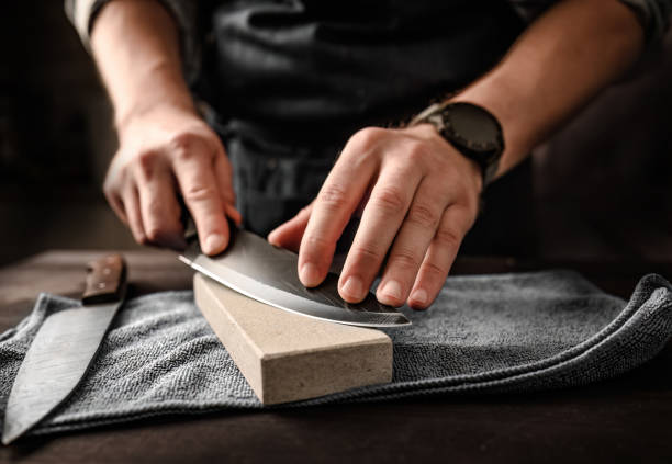 hombre afilando un cuchillo con piedra de afilar - afilado fotografías e imágenes de stock