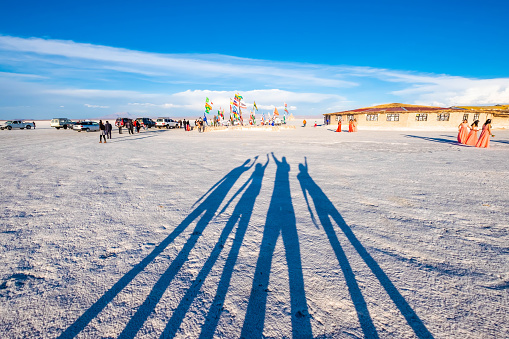 Salar de Uyuni, Bolivia - 21 October 2018: Shadow of four people with raised hands on white surface
