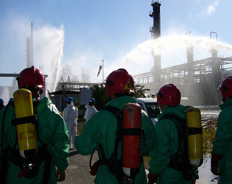 Firefighters crew wearing green coveralls and equipped with a tank of compressed air and a mask for Chemical Accident and Toxic Risk