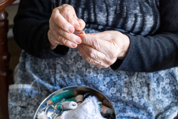 istock Close-up, hands of a senior woman threading a needle with thread. 1490637794