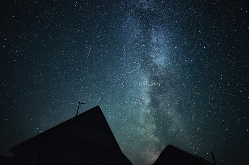 Stars sky and milky way above roofs in countryside