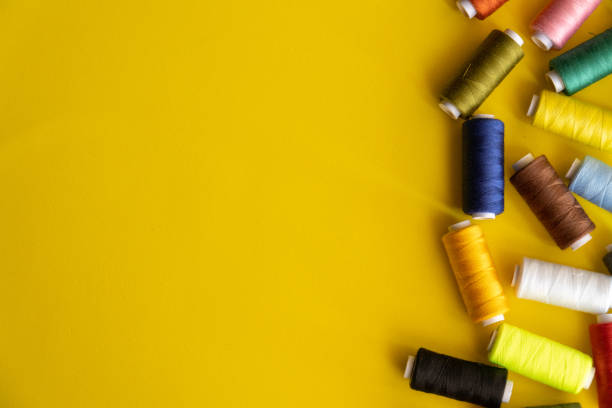 istock Many spools of thread for sewing of various colors, on a yellow background with space for text. 1490637958