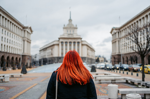 Rear-view of the young plus size woman on the town square in Sofia, Bulgaria. Enjoying the view of the Largo on the Independence Square.