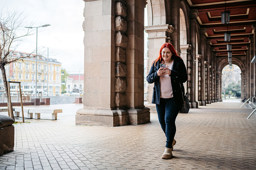 Young plus size woman using her smart phone on the street in Sofia, Bulgaria.