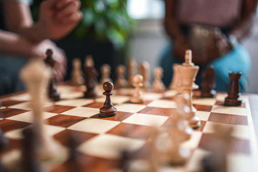 A happy multiracial family comes together to enjoy the pleasures of family game night. They sit in the living room, playing chess and sharing laughs.