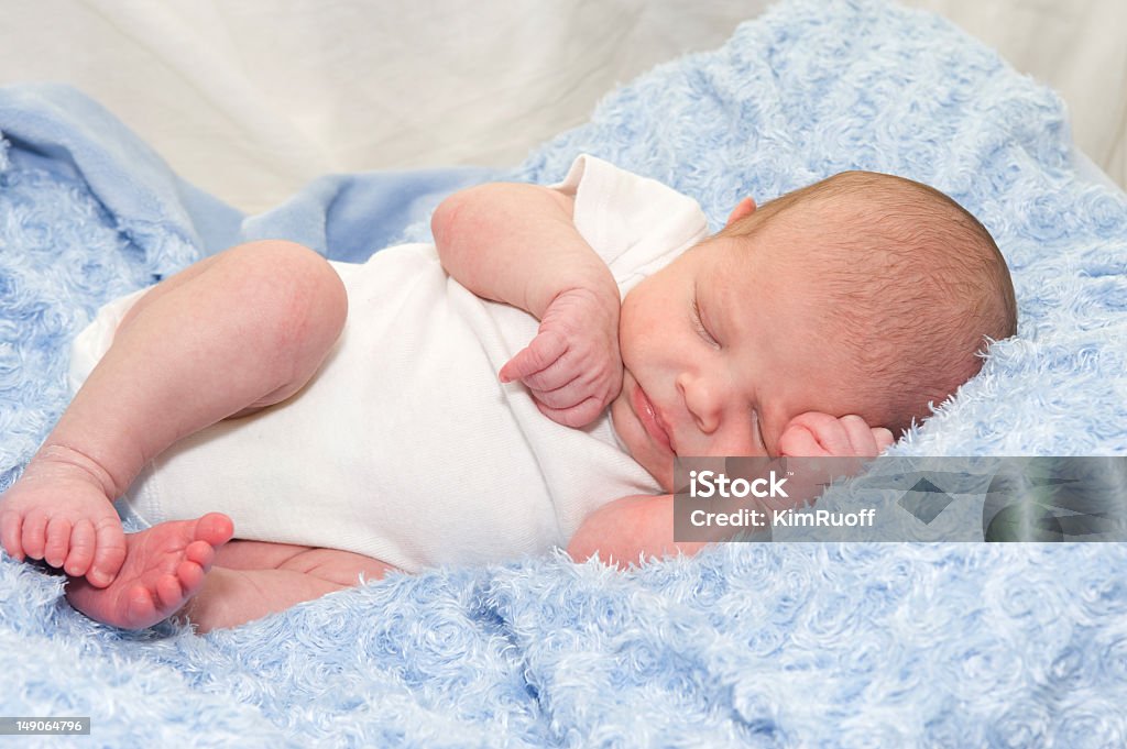 Newborn baby in white sleeping on a blue blanket Newborn baby boy lying on blue blanket Baby - Human Age Stock Photo