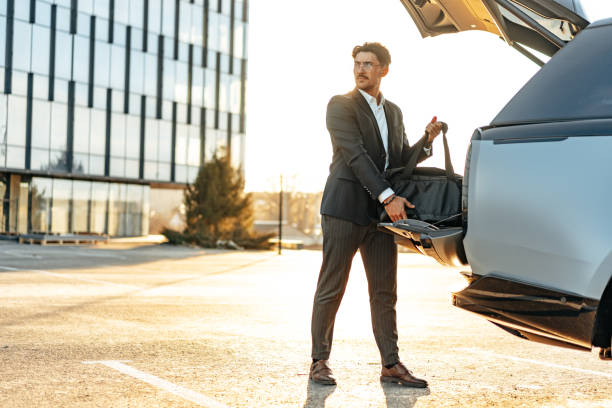 Successful businessman taking luggage from the car trunk outdoors