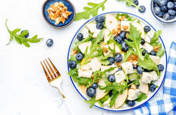 istock Gourmet summer salad with sweet pears, blueberries, blue cheese, arugula and walnuts. White kitchen table background, top view 1490654541