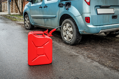 Red metal fuel tank for transporting and storing petrol. Filling the car from the canister. Transportation theme