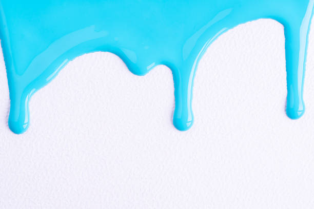 istock Light blue liquid drops of paint color flow down on white canvas. Blue paint dripping on the white wall with copy space. 1490655830