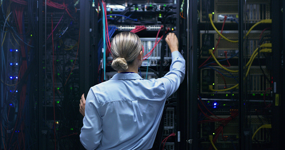 Woman, server room and night with cable inspection, connectivity check or maintenance for IT job. Female engineer, fiber connection or information technology for cybersecurity, storage or data center
