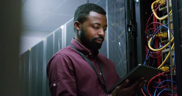 istock Engineer man, tablet and server room in night for cable inspection, connection check and analysis for IT job. African technician, touchscreen and information technology for cybersecurity in workplace 1490657759