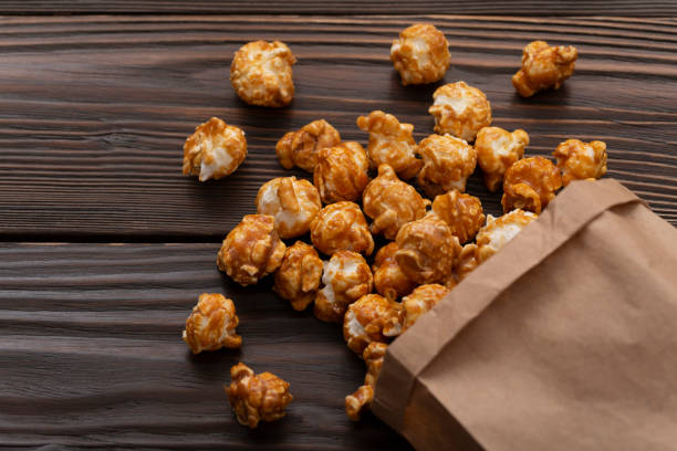 istock Caramelized popcorn in paper bag with copy space on wooden kitchen table flat lay 1490657791